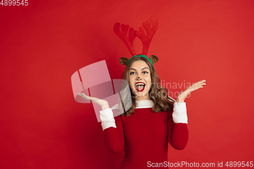 Image of Beautiful woman like Christmas deer isolated on red background. Concept of 2021 New Year\'s, winter mood, holidays.