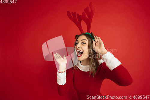 Image of Beautiful woman like Christmas deer isolated on red background. Concept of 2021 New Year\'s, winter mood, holidays.