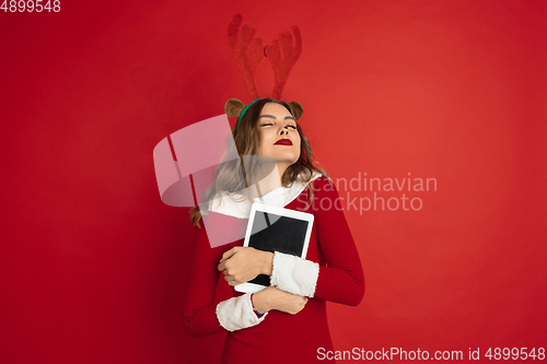 Image of Beautiful woman like Christmas deer isolated on red background. Concept of 2021 New Year\'s, winter mood, holidays.