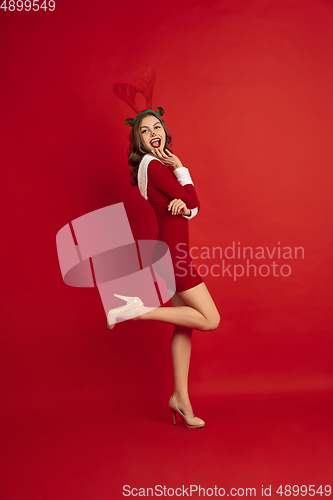 Image of Beautiful woman like Christmas deer isolated on red background. Concept of 2021 New Year\'s, winter mood, holidays.