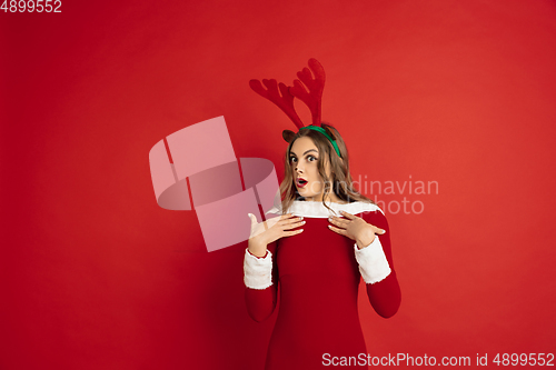 Image of Beautiful woman like Christmas deer isolated on red background. Concept of 2021 New Year\'s, winter mood, holidays.