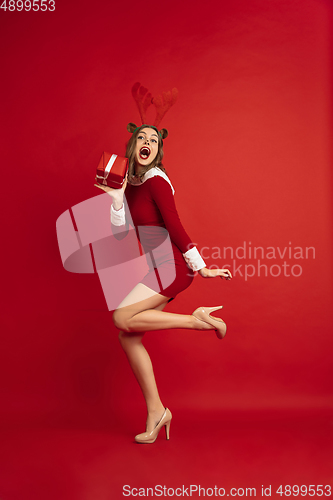 Image of Beautiful woman like Christmas deer isolated on red background. Concept of 2021 New Year\'s, winter mood, holidays.