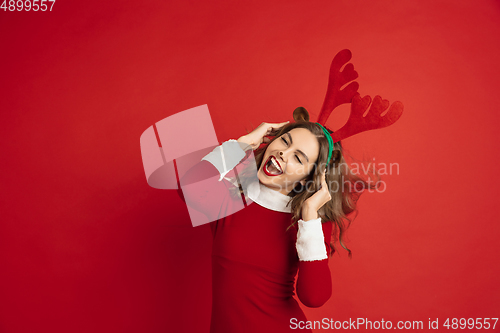 Image of Beautiful woman like Christmas deer isolated on red background. Concept of 2021 New Year\'s, winter mood, holidays.