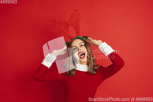 Image of Beautiful woman like Christmas deer isolated on red background. Concept of 2021 New Year\'s, winter mood, holidays.