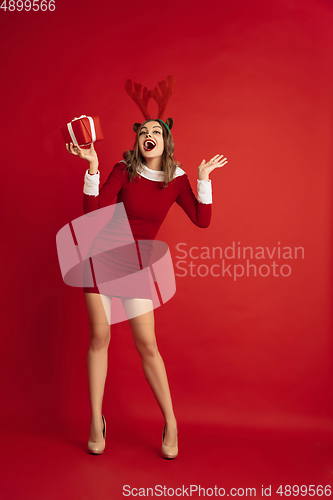 Image of Beautiful woman like Christmas deer isolated on red background. Concept of 2021 New Year\'s, winter mood, holidays.