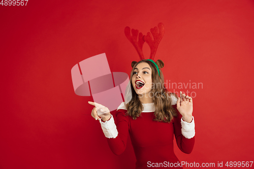 Image of Beautiful woman like Christmas deer isolated on red background. Concept of 2021 New Year\'s, winter mood, holidays.