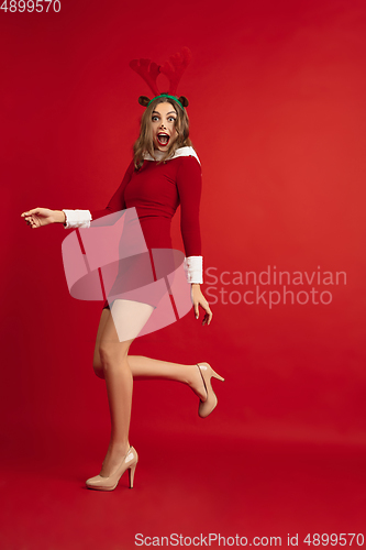 Image of Beautiful woman like Christmas deer isolated on red background. Concept of 2021 New Year\'s, winter mood, holidays.