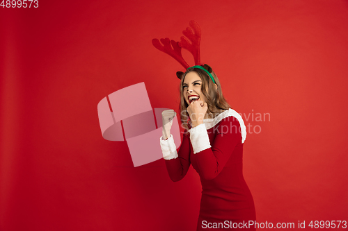 Image of Beautiful woman like Christmas deer isolated on red background. Concept of 2021 New Year\'s, winter mood, holidays.