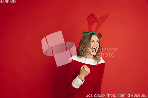 Image of Beautiful woman like Christmas deer isolated on red background. Concept of 2021 New Year\'s, winter mood, holidays.