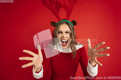 Image of Beautiful woman like Christmas deer isolated on red background. Concept of 2021 New Year\'s, winter mood, holidays.