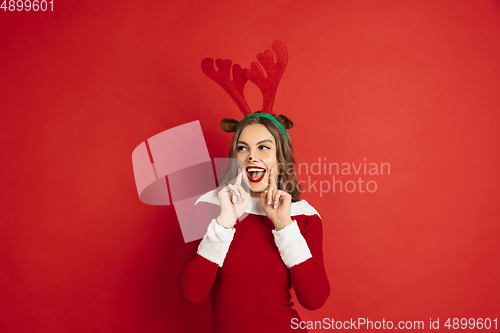 Image of Beautiful woman like Christmas deer isolated on red background. Concept of 2021 New Year\'s, winter mood, holidays.