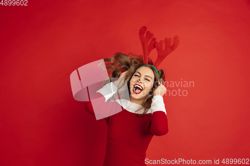 Image of Beautiful woman like Christmas deer isolated on red background. Concept of 2021 New Year\'s, winter mood, holidays.