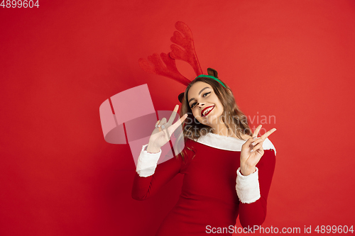 Image of Beautiful woman like Christmas deer isolated on red background. Concept of 2021 New Year\'s, winter mood, holidays.