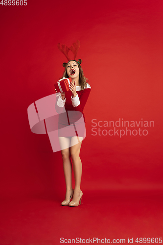 Image of Beautiful woman like Christmas deer isolated on red background. Concept of 2021 New Year\'s, winter mood, holidays.