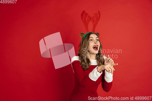 Image of Beautiful woman like Christmas deer isolated on red background. Concept of 2021 New Year\'s, winter mood, holidays.