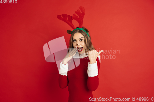 Image of Beautiful woman like Christmas deer isolated on red background. Concept of 2021 New Year\'s, winter mood, holidays.