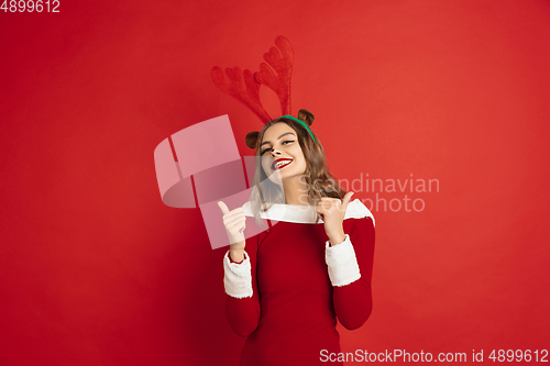 Image of Beautiful woman like Christmas deer isolated on red background. Concept of 2021 New Year\'s, winter mood, holidays.