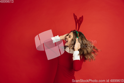 Image of Beautiful woman like Christmas deer isolated on red background. Concept of 2021 New Year\'s, winter mood, holidays.