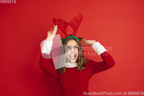 Image of Beautiful woman like Christmas deer isolated on red background. Concept of 2021 New Year\'s, winter mood, holidays.