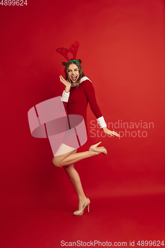 Image of Beautiful woman like Christmas deer isolated on red background. Concept of 2021 New Year\'s, winter mood, holidays.