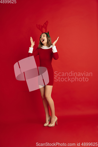 Image of Beautiful woman like Christmas deer isolated on red background. Concept of 2021 New Year\'s, winter mood, holidays.