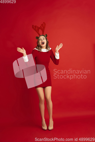 Image of Beautiful woman like Christmas deer isolated on red background. Concept of 2021 New Year\'s, winter mood, holidays.