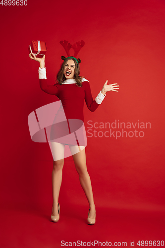 Image of Beautiful woman like Christmas deer isolated on red background. Concept of 2021 New Year\'s, winter mood, holidays.