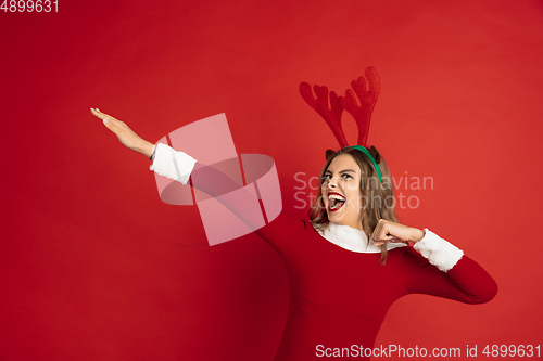 Image of Beautiful woman like Christmas deer isolated on red background. Concept of 2021 New Year\'s, winter mood, holidays.