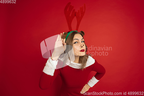 Image of Beautiful woman like Christmas deer isolated on red background. Concept of 2021 New Year\'s, winter mood, holidays.