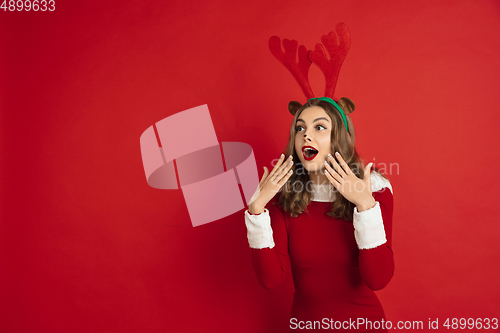 Image of Beautiful woman like Christmas deer isolated on red background. Concept of 2021 New Year\'s, winter mood, holidays.