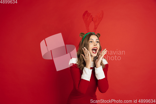 Image of Beautiful woman like Christmas deer isolated on red background. Concept of 2021 New Year\'s, winter mood, holidays.