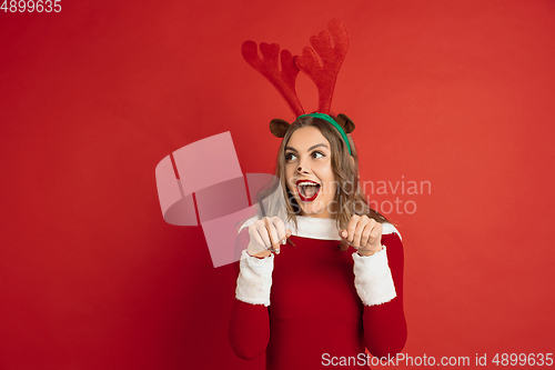 Image of Beautiful woman like Christmas deer isolated on red background. Concept of 2021 New Year\'s, winter mood, holidays.