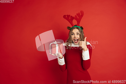 Image of Beautiful woman like Christmas deer isolated on red background. Concept of 2021 New Year\'s, winter mood, holidays.