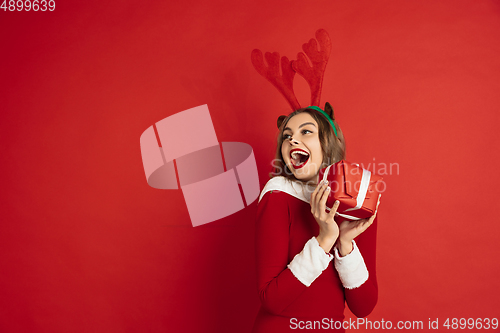 Image of Beautiful woman like Christmas deer isolated on red background. Concept of 2021 New Year\'s, winter mood, holidays.