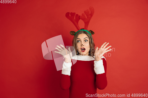 Image of Beautiful woman like Christmas deer isolated on red background. Concept of 2021 New Year\'s, winter mood, holidays.