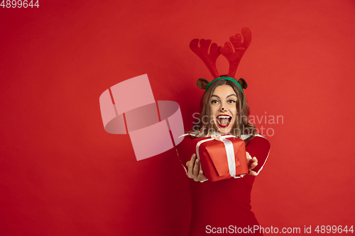 Image of Beautiful woman like Christmas deer isolated on red background. Concept of 2021 New Year\'s, winter mood, holidays.