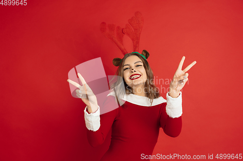 Image of Beautiful woman like Christmas deer isolated on red background. Concept of 2021 New Year\'s, winter mood, holidays.