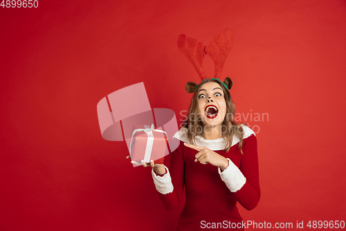 Image of Beautiful woman like Christmas deer isolated on red background. Concept of 2021 New Year\'s, winter mood, holidays.