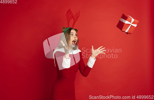 Image of Beautiful woman like Christmas deer isolated on red background. Concept of 2021 New Year\'s, winter mood, holidays.