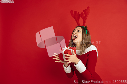 Image of Beautiful woman like Christmas deer isolated on red background. Concept of 2021 New Year\'s, winter mood, holidays.