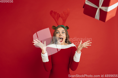 Image of Beautiful woman like Christmas deer isolated on red background. Concept of 2021 New Year\'s, winter mood, holidays.