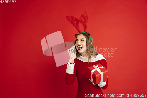 Image of Beautiful woman like Christmas deer isolated on red background. Concept of 2021 New Year\'s, winter mood, holidays.