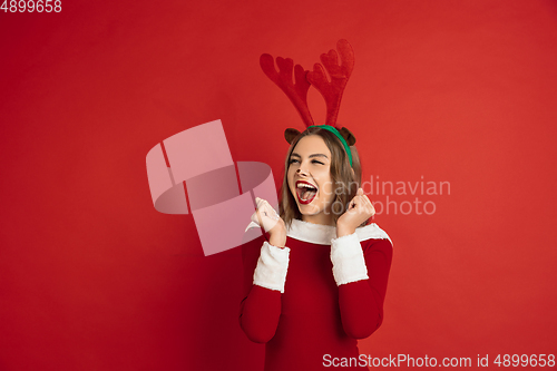 Image of Beautiful woman like Christmas deer isolated on red background. Concept of 2021 New Year\'s, winter mood, holidays.