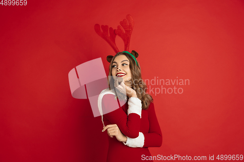 Image of Beautiful woman like Christmas deer isolated on red background. Concept of 2021 New Year\'s, winter mood, holidays.