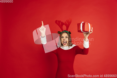 Image of Beautiful woman like Christmas deer isolated on red background. Concept of 2021 New Year\'s, winter mood, holidays.