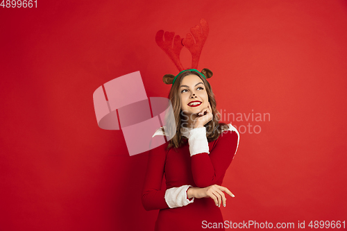 Image of Beautiful woman like Christmas deer isolated on red background. Concept of 2021 New Year\'s, winter mood, holidays.