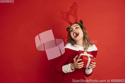 Image of Beautiful woman like Christmas deer isolated on red background. Concept of 2021 New Year\'s, winter mood, holidays.