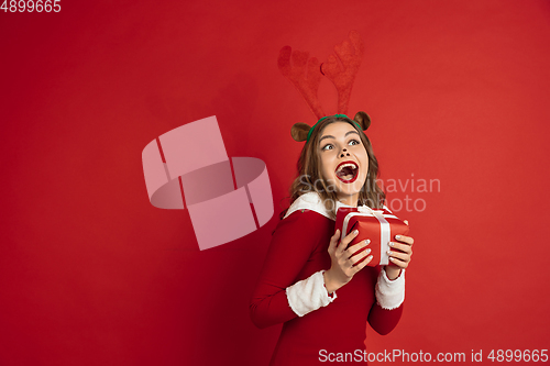 Image of Beautiful woman like Christmas deer isolated on red background. Concept of 2021 New Year\'s, winter mood, holidays.