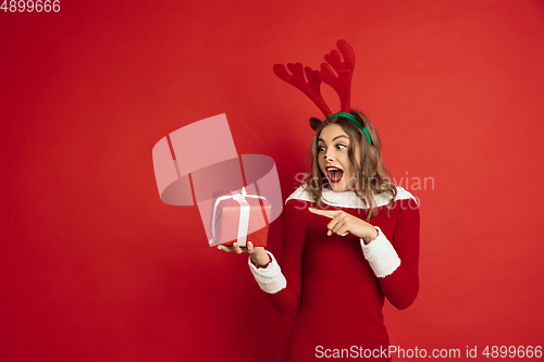 Image of Beautiful woman like Christmas deer isolated on red background. Concept of 2021 New Year\'s, winter mood, holidays.