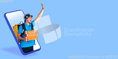 Image of Handsome delivery man giving order right from smartphone\'s screen, fast delivery concept